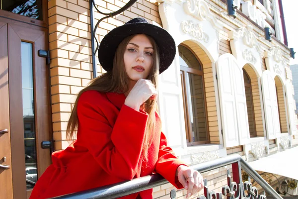 Menina bonita em um casaco vermelho e chapéu preto — Fotografia de Stock