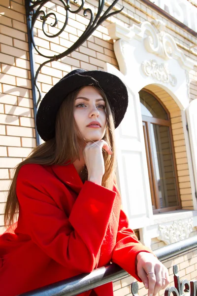 Beautiful girl in a red coat and black hat — Stock Photo, Image