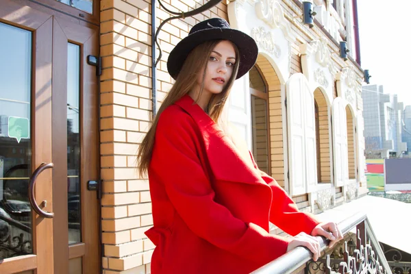 Menina bonita em um casaco vermelho e chapéu preto — Fotografia de Stock