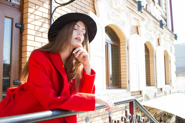 Hermosa chica con un abrigo rojo y sombrero negro — Foto de Stock