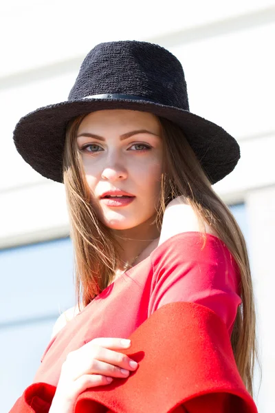 Menina bonita em um casaco vermelho e chapéu preto — Fotografia de Stock