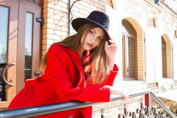 Beautiful girl in a red coat and black hat — Stock Photo, Image