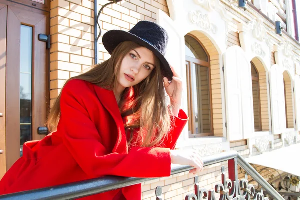 Mooi meisje in een rode jas en zwarte hoed — Stockfoto