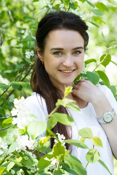 Ung flicka på en bakgrund av en blommande fågel körsbär — Stockfoto