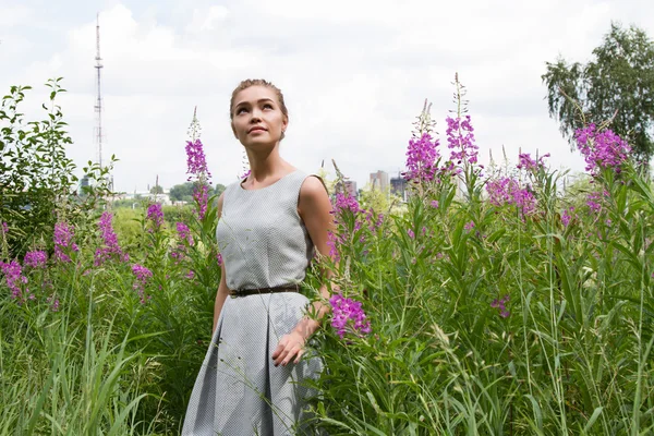 Menina caminha no campo entre flores silvestres — Fotografia de Stock