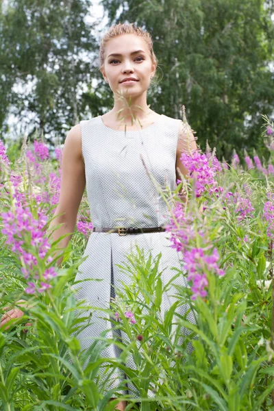 Meisje loopt in het platteland tussen de wilde bloemen — Stockfoto