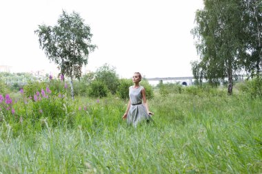 Uzun otların ve kır çiçekleri ile sahada kız gider