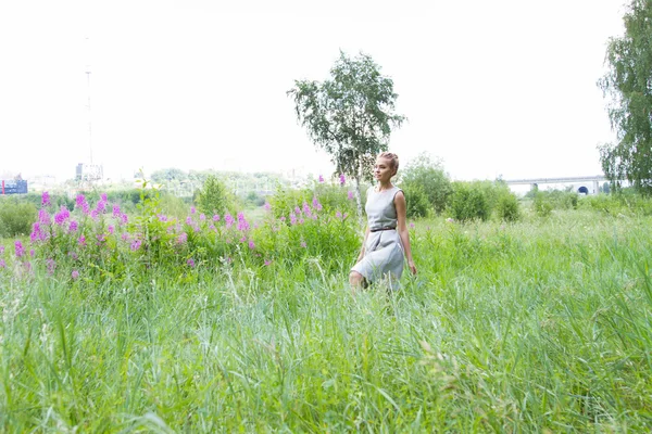 Girl goes on the field with tall grass and wildflowers — Stock Photo, Image