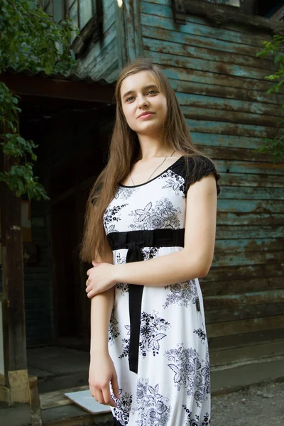 Young girl on the background of the old wooden building — Stock Photo, Image