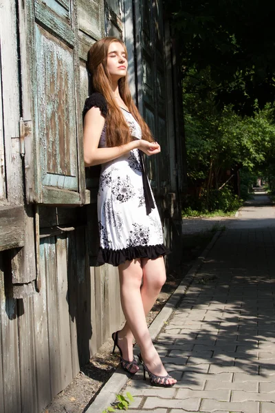 Young girl on the background of the old wooden building. — Stock Photo, Image