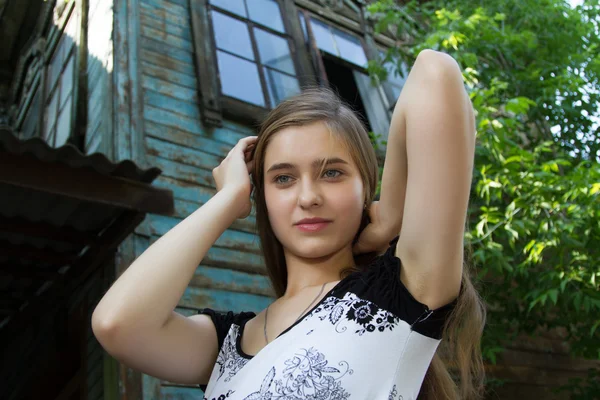 Gadis muda yang cantik di latar belakang rumah kayu tua — Stok Foto