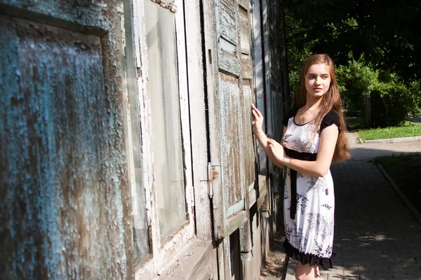 Schöne junge Mädchen auf dem Hintergrund des alten Holzhauses. — Stockfoto