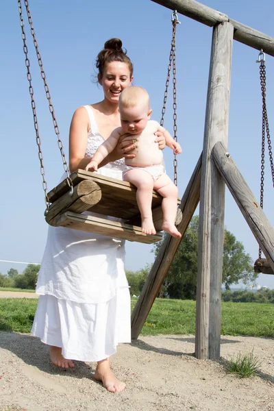 Mamá con un niño en un columpio — Foto de Stock