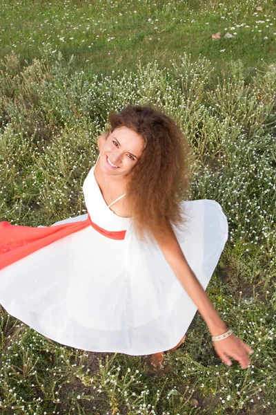 Chica en vestido blanco en el campo entre flores silvestres — Foto de Stock