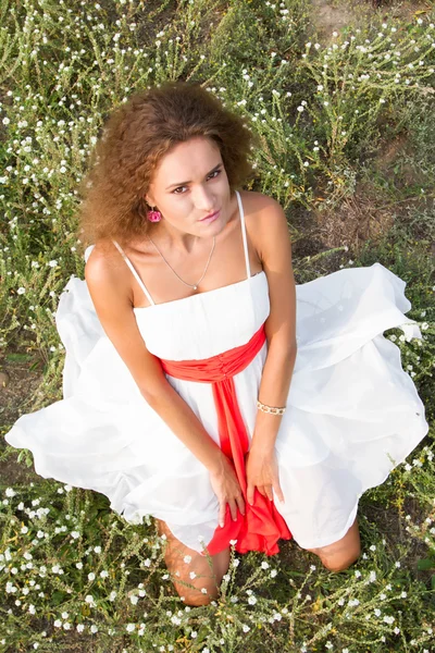 Девушка в белом платье в поле среди полевых цветов — стоковое фото