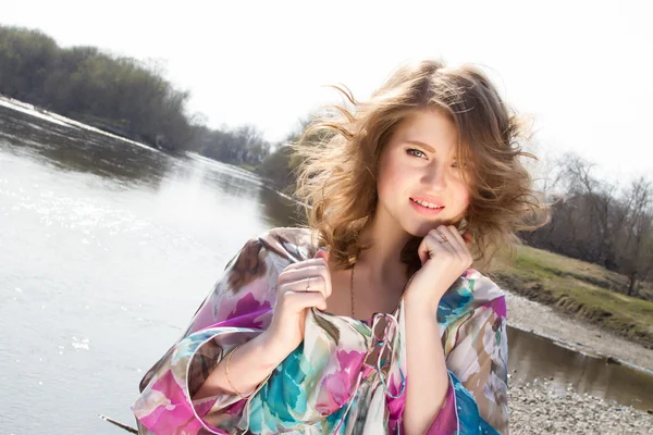 Meisje op de oever van de rivier met de ontwikkeling van het haar van de wind — Stockfoto