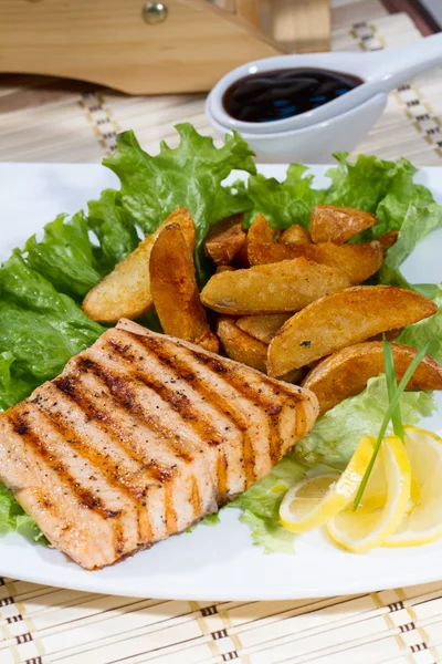 Fried sturgeon with french fries and lemon on a white plate