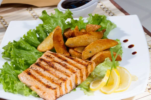 Esturjão frito com batatas fritas e limão em um prato branco — Fotografia de Stock