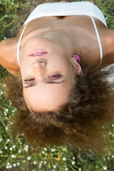 野生の花の背景に巻き毛の少女。夏の肖像画. — ストック写真