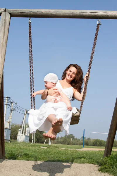 Mamá con un niño en un paseo swing — Foto de Stock