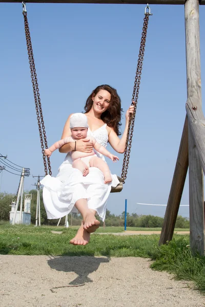 Mamá con un niño en un paseo swing — Foto de Stock