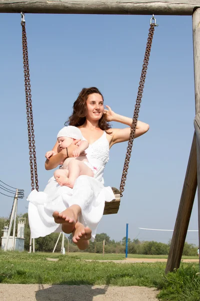 Mamá con un niño en un paseo swing — Foto de Stock