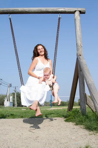 Mamá con un niño en un paseo swing — Foto de Stock