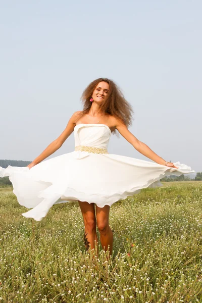 Chica en vestido blanco en el campo entre flores silvestres —  Fotos de Stock