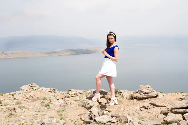 Schönes junges Mädchen steht auf einem hohen Berg im Hintergrund des Baikalsees — Stockfoto