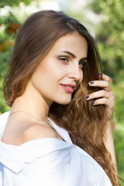 Junges Mädchen mit langen Haaren im Park vor einem Hintergrund aus Eberesche — Stockfoto