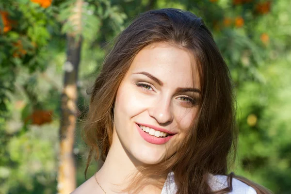 Young girl with long hair in the park on a background of mountain ash — Stock Photo, Image