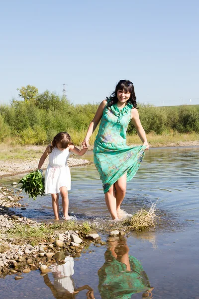 Mamá y su hija corriendo en el agua — Foto de Stock