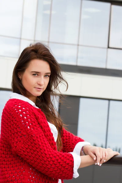 Business woman in a red cardigan and white shirt on the background of office building — Stock Photo, Image