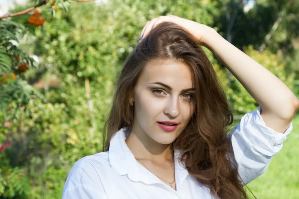 Young girl with long hair and a white shirt on a park background — Stock Photo, Image