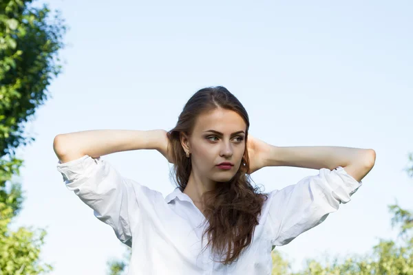 Young girl with long hair and a white shirt on a park background — Stock Photo, Image