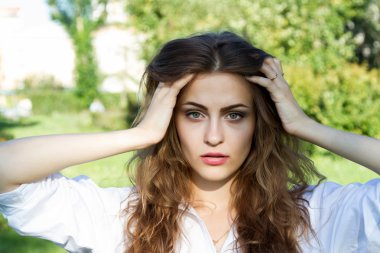 Uzun saçlı ve yaz parkta beyaz bir gömlek giymiş güzel genç kız