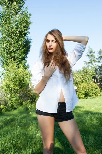 Menina bonita em uma camisa branca andando no parque . — Fotografia de Stock