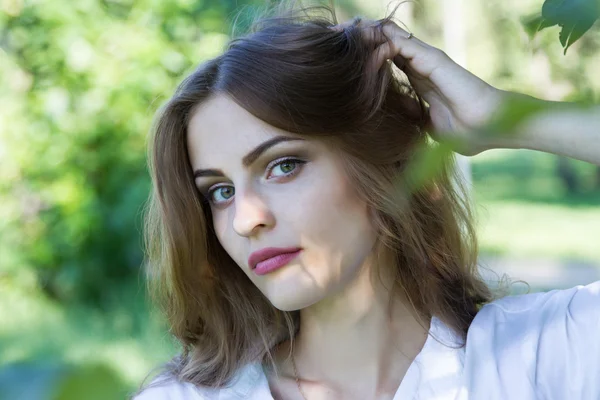 Hermosa joven con una camisa blanca caminando en el parque . — Foto de Stock