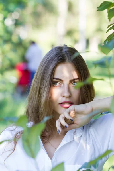Hermosa joven con una camisa blanca caminando en el parque . — Foto de Stock
