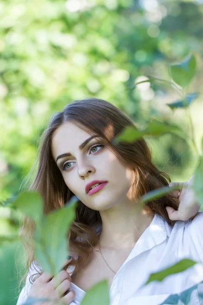 Beautiful young girl in a white shirt walking in the park — Stock Photo, Image