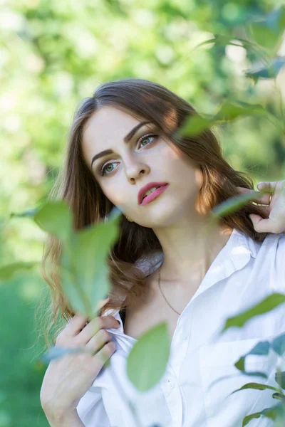 Beautiful young girl in a white shirt walking in the park — Stock Photo, Image