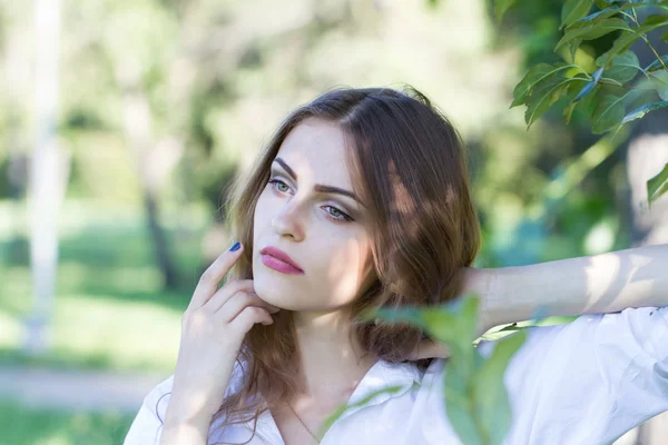 Hermosa joven con una camisa blanca caminando en el parque . — Foto de Stock