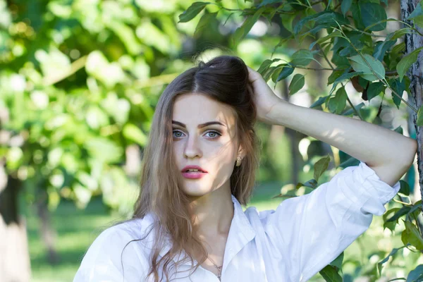 Hermosa joven con una camisa blanca caminando en el parque . — Foto de Stock