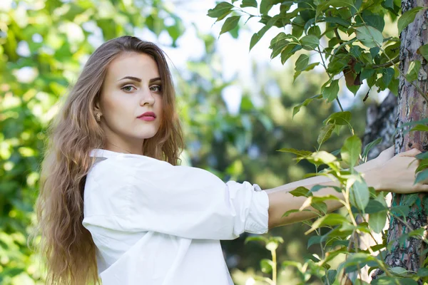 Hermosa joven con una camisa blanca caminando en el parque . — Foto de Stock