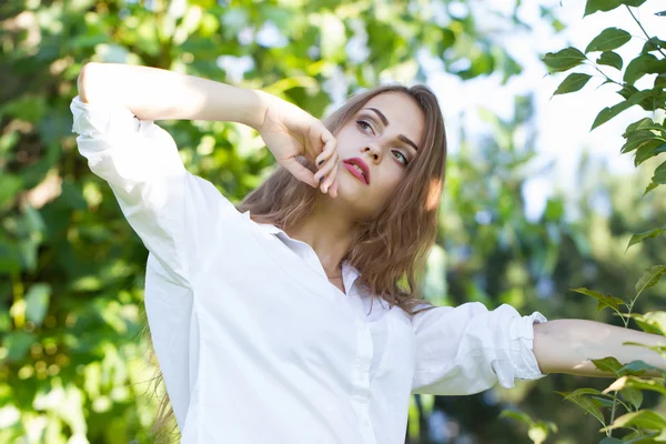 Mooi jong meisje in een wit overhemd wandelen in het park. — Stockfoto