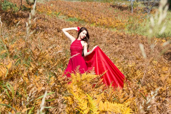 Mädchen im roten Abendkleid zwischen den gelben Blättern eines Farns — Stockfoto