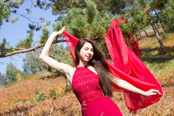 Mädchen im roten Abendkleid zwischen den gelben Blättern eines Farns — Stockfoto