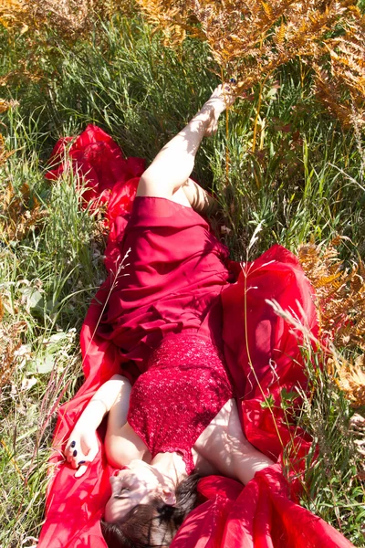 Ragazza in abito da sera rosso è in alta erba autunno — Foto Stock