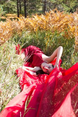 Sonbahar çimleri yalan kırmızı akşam elbiseli kız
