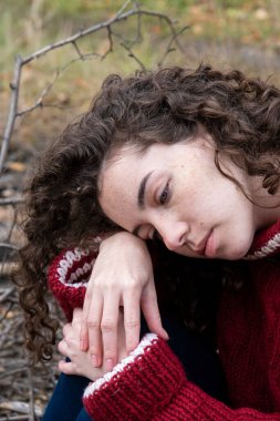 Sonbahar ormanında, sıcak örülü kazak giyen bir kız.